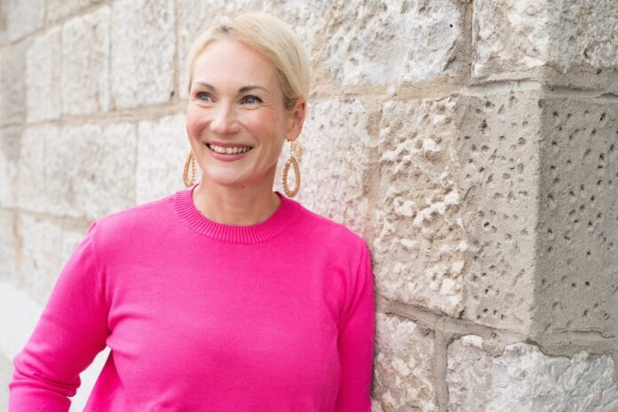 Sichtbarkeit Anke Ames angelent an einer Steinwand in einem Pinkfarbenen Oberteil! Foto©Schmelz Fotodesign Anke Ames